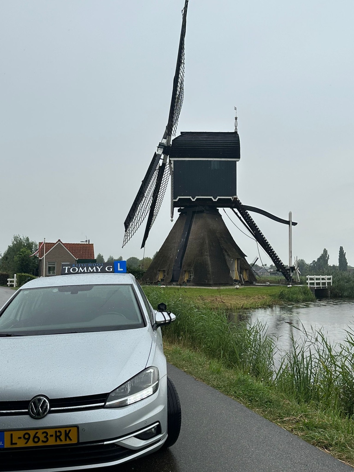 De lesauto van Rijschool Tommy G bij een molen in de Krimpenerwaard
