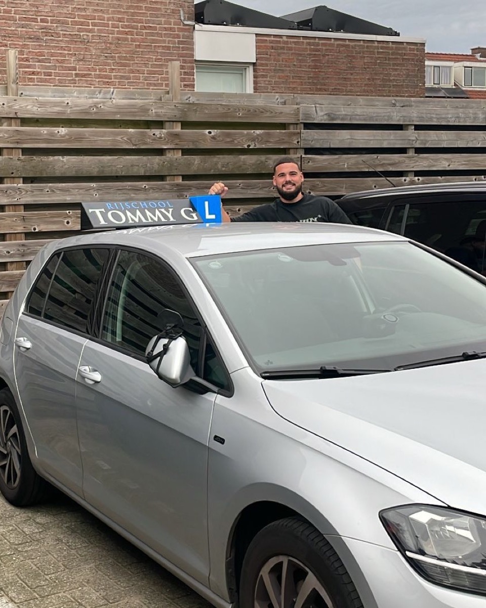 Tom Groenewold naast zijn lesauto van Rijschool Tommy G
